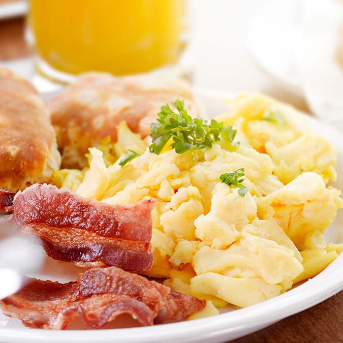 Scrambled eggs and crispy bacon at E.J.'s Diner Wausau, garnished with parsley and biscuits.